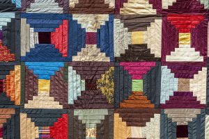Detail of a silk quilt in red, blue, yellow, and brown showing an apple core pattern.