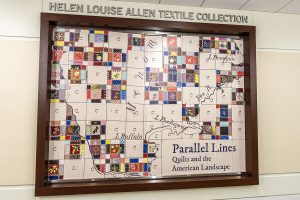 Photo of an interior window framed in wood and covered in a large graphic showing pieces of a quilt and map