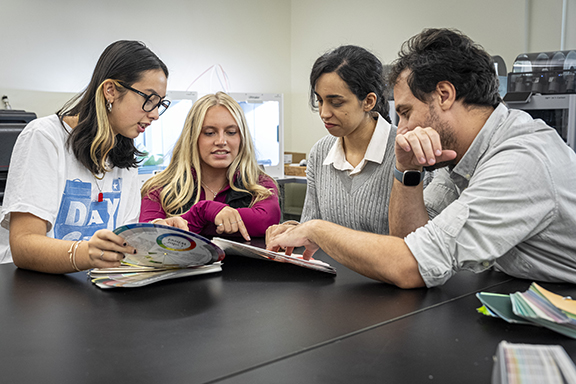 Photo of people seated around a table discussing and looking at a color wheel