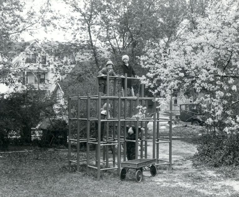 Several children climb on a jungle gym in the Dorothy Roberts Nursery School playground at the School of Home Economics." The UW–Madison Collection ca. 1930. Back of photo, "Dorothy Roberts Nursery School playground published in the 1930 home economic course catalog